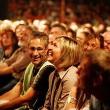 A comedian performing stand-up comedy for a laughing audience.