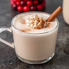 Whole cloves beside a glass of eggnog