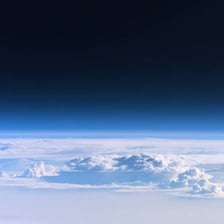 Earth’s atmosphere visible as a thin layer around the planet.