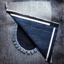 A denim jeans leg repaired with a patch over the knee.