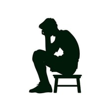 A person sitting alone with a gloomy expression.