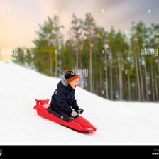 A child riding a sled down a snow-covered hill