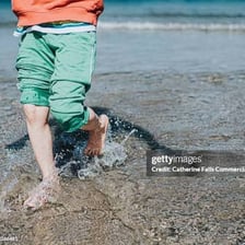Person moving through shallow water with splashes.