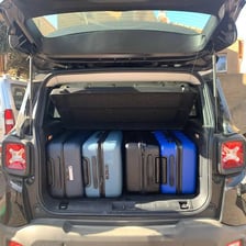 A car trunk tightly packed with suitcases and travel bags.