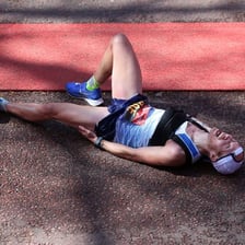 A tired runner rubbing sore leg muscles after a race.