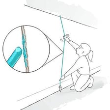A plumb line hanging vertically beside a wall.