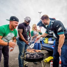 Fans tailgating around vehicles in a parking lot.