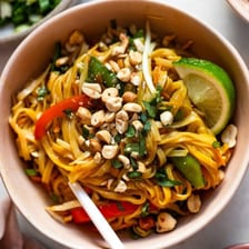 A plate of Pad Thai noodles garnished with peanuts and lime.