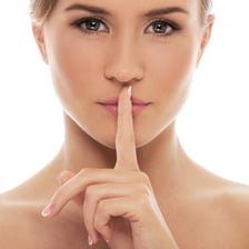 A person holding a finger to their lips in a quiet gesture