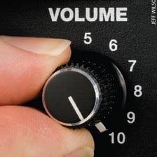 A musician adjusting the volume on a guitar amplifier