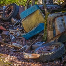 A heavily rusted car in a junkyard.
