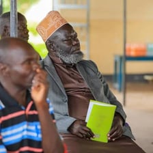 A respected older community leader speaking at a meeting.