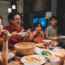 People beginning a meal together at a dining table.