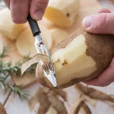 A handheld vegetable peeler being used on a potato.