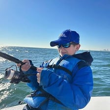 An angler winding a fish toward shore with a fishing rod