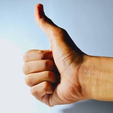 A hand giving a thumbs-up gesture to indicate approval.