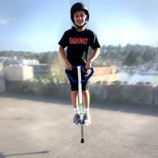 A child balancing on and bouncing with a pogo stick