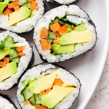 Sliced avocado sushi rolls on a plate