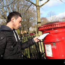 A person placing a letter into a postal mailbox.