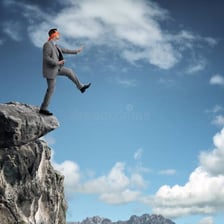 A person crossing a narrow ledge on a mountain.