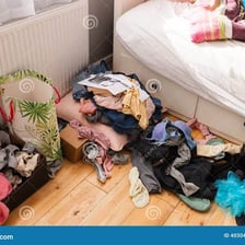 Clothes and belongings scattered around a messy bedroom.