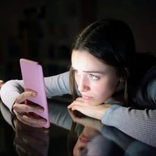 A person checking a phone while appearing anxious about a social event.