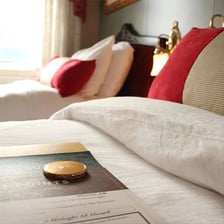 A hotel room prepared with folded-back bed covers for turndown service