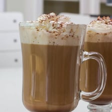 A café mocha topped with foam in a coffeehouse setting.