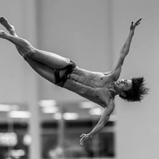 A diver twisting in midair after jumping from a platform.