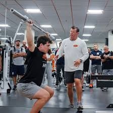 An expert coach demonstrating a technique to a group of athletes