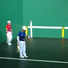 A jai alai player holding a curved cesta on the court.