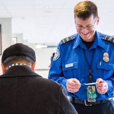 A Transportation Security Administration officer checking a traveler’s identification at an airport.