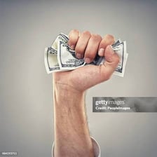 A hand holding a thick wad of dollar bills