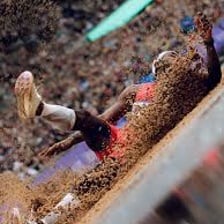 A long jumper landing in the sandpit during a competition.