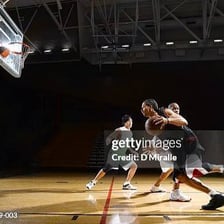 Basketball players competing on an indoor court.