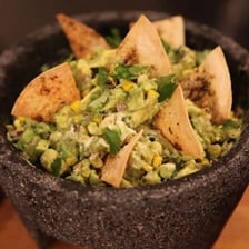 A bowl of guacamole served with tortilla chips
