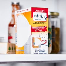 An open refrigerator with a box of baking soda used for odor control.