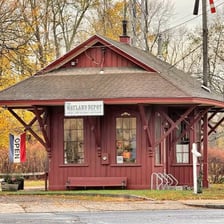 A railroad train stopped beside a station depot.
