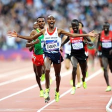 A runner moving around a marked athletics track.