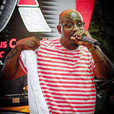A hip-hop performer raps into a microphone on stage.