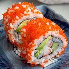 Orange fish roe arranged on a piece of sushi.