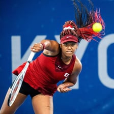 Naomi Osaka playing tennis during a professional match.