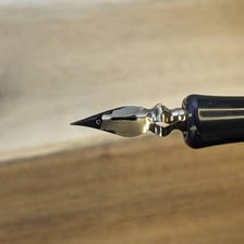 A calligraphy pen making a dark ink stroke on paper.