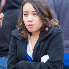 A person wrapped in warm clothing and visibly reacting to cold weather.