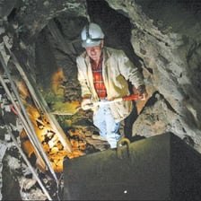 A miner holding a piece of mineral-bearing ore.