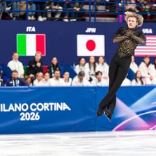 A figure skater airborne during an axel jump
