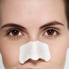 A person with a pore-cleansing strip applied across the nose.