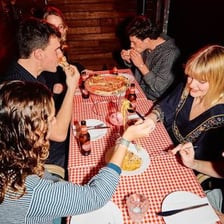 Diners seated at a table with plates of food in a playful eating contest