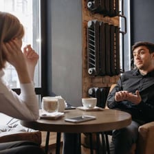 Two people talking over coffee at a cafe.