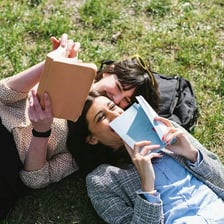 One person handing a book to another person as a loan.